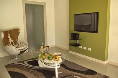 a living room with a table and a chair and a television at La Conchiglia Case Vacanze in Balestrate