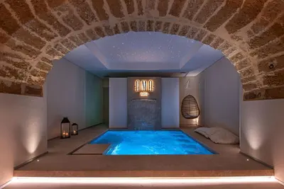 a large swimming pool in a room with a brick wall at Costamante Suites & Spa in Castellammare del Golfo