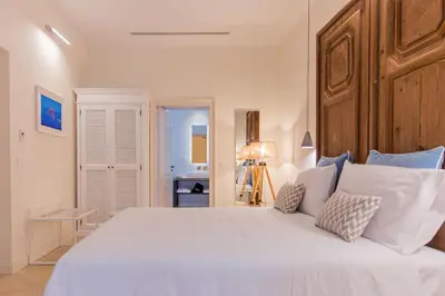 a bedroom with a large white bed with a wooden headboard at Costamante Suites & Spa in Castellammare del Golfo