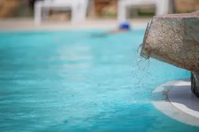 a pool with water pouring out of the side of asevere at Casale la Macina Residence Scopello in Scopello