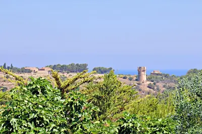 a group of trees with a tower in the background at Casale la Macina Residence Scopello in Scopello