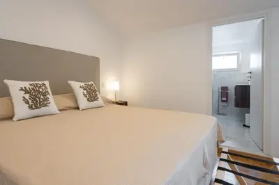 a white bedroom with a large bed with two pillows at Politeama rooftop in Palermo