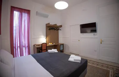 a bedroom with a bed and a table and a desk at Petrarca Suite in Palermo