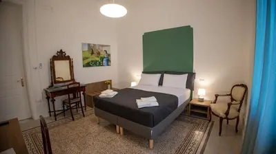a bedroom with a bed with a green headboard and a mirror at Petrarca Suite in Palermo