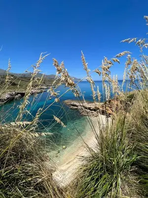 a view of the ocean from a beach with tall grass at Cala Bianca (The One&Only) in Castellammare del Golfo