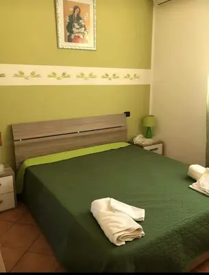a bedroom with a green bed and a mirror at appartamento in villa splendente in Castellammare del Golfo