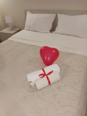 a red heart sitting next to a bed with a towel at Casa TerraMare in Palermo