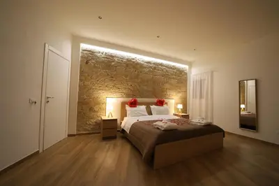 a bedroom with a large bed and a stone wall at Boscò Suites in Carini