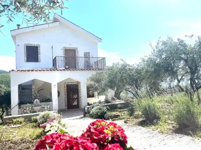 a white house with a balcony and flowers at Villetta con Oliveto CFG in Prizzi