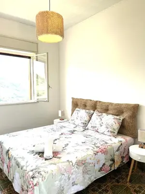 a bedroom with a bed with a floral bedspread and a window at Villetta con Oliveto CFG in Prizzi