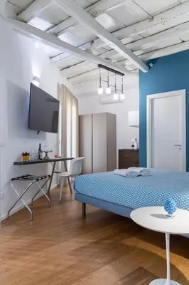 a bedroom with a blue bed and a table at Peonia Boutique Apartments in Palermo