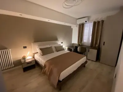 a bedroom with a bed and a desk with a lamp at Hotel Plaza Ungheria in Palermo