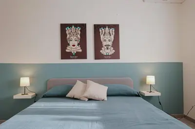 a bedroom with a bed with three pictures on the wall at Casa Makira in Terrasini