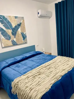 a bedroom with a bed with a blue comforter at Chalaroste home in Terrasini