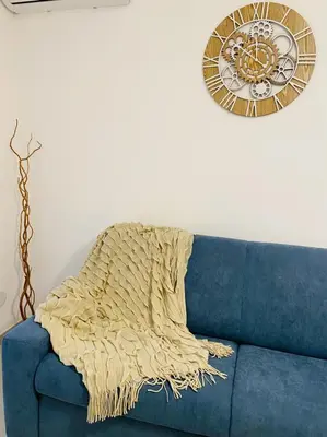 a blanket on a blue couch with a clock on the wall at Chalaroste home in Terrasini