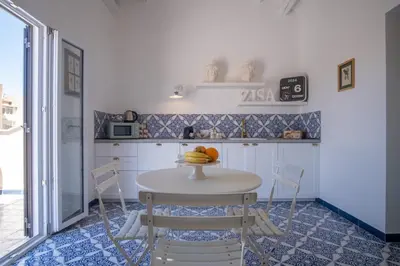 a kitchen with white cabinets and a table at Zisa Top Romantic Terrace & Private outdoor Jacuzzi in Palermo
