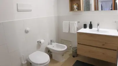 a white bathroom with a toilet and a sink at Bonello House Cattedrale in Palermo