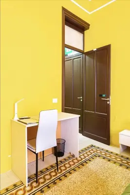 a yellow room with a desk and a white chair at Bohème B&B in Palermo