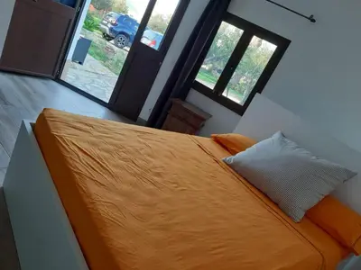 a bed with an orange comforter in a room with windows at Camera Tina in Castellammare del Golfo