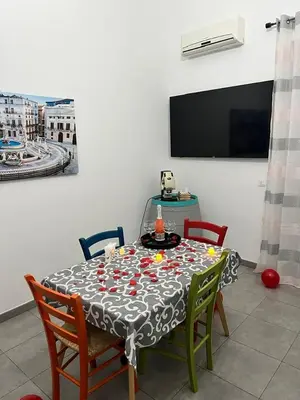 a dining room with a table with chairs and a tv at La Casa di Bella in Palermo