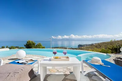a white table and chairs next to a swimming pool at Villa vista mare con piscina a Sarmuci in Castellammare del Golfo