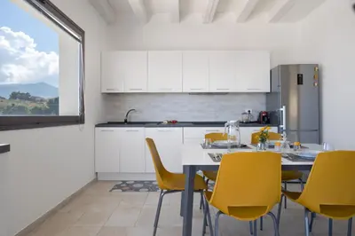 a kitchen with a table and yellow chairs at Villa vista mare con piscina a Sarmuci in Castellammare del Golfo
