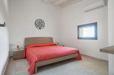 a bedroom with a bed with a red blanket at Villa vista mare con piscina a Sarmuci in Castellammare del Golfo