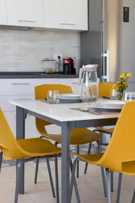 a white table with yellow chairs in a kitchen at Villa vista mare con piscina a Sarmuci in Castellammare del Golfo