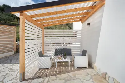 a pergola with two chairs and a table on a patio at Villa vista mare con piscina a Sarmuci in Castellammare del Golfo