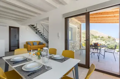 a dining room and living room with a table and chairs at Villa vista mare con piscina a Sarmuci in Castellammare del Golfo