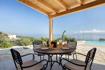 a patio with a table and chairs and a pool at Villa vista mare con piscina a Sarmuci in Castellammare del Golfo