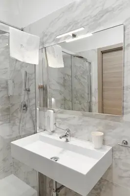 a white bathroom with a sink and a mirror at Kalsa Sicilian Rooms in Partinico