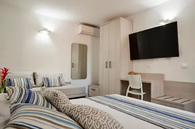 a hotel room with two beds and a flat screen tv at Kalsa Sicilian Rooms in Partinico