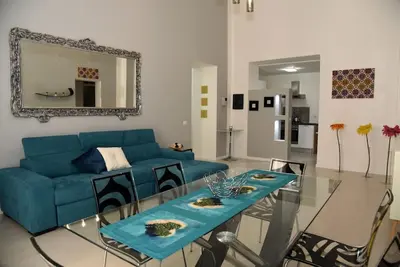 a living room with a blue couch and a glass table at Briaria Apartment in Palermo