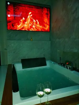 two wine glasses sitting next to a bathtub with a fire at I Cappuccini Suite in Palermo