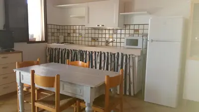 a kitchen with a table and chairs and a white refrigerator at Terrazza sul mare Scopello in Scopello