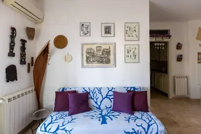 a bedroom with a bed with purple pillows and pictures on the wall at Isola delle Femmine Holiday in Isola delle Femmine