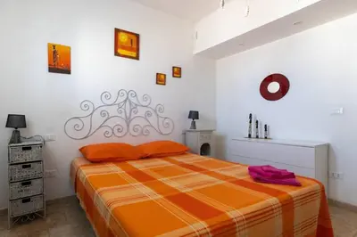 a bedroom with a bed with an orange blanket at Isola delle Femmine Holiday in Isola delle Femmine