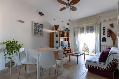 a kitchen and living room with a table and a couch at Isola delle Femmine Holiday in Isola delle Femmine