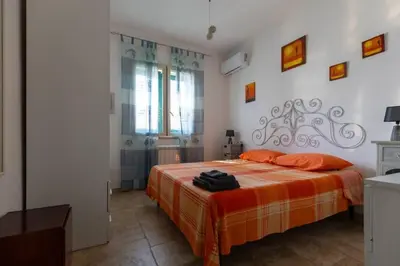 a bedroom with a bed with an orange blanket at Isola delle Femmine Holiday in Isola delle Femmine