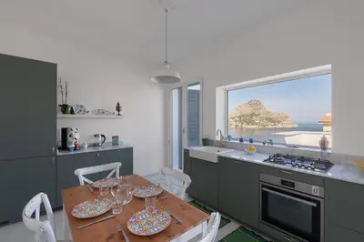 a kitchen with a table and chairs and a window at Solemar Sicilia - Casa Margherita in Santa Flavia