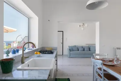 a kitchen with a sink and a living room at Solemar Sicilia - Casa Margherita in Santa Flavia