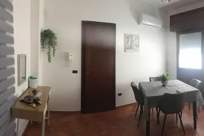 a dining room with a table and a wooden door at Alloggio incantevole/ bedsitting-room in Altavilla Milicia