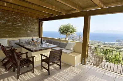 a table and chairs on a balcony with a view of the ocean at Villa Fenice in Scopello