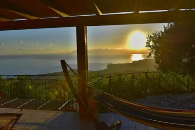 a view of the sunset from a porch with a hammock at Villa Fenice in Scopello