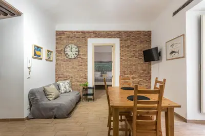 a living room with a table and a clock on a wall at Borsa Apartments by Wonderful Italy in Palermo