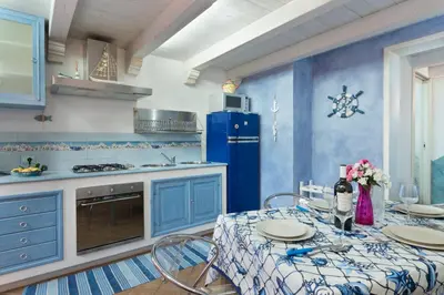 a blue kitchen with a table and a blue refrigerator at Cambusa del Capitano in San Vito lo Capo