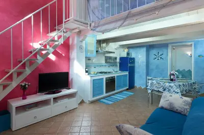 a living room with a blue couch and a staircase at Cambusa del Capitano in San Vito lo Capo