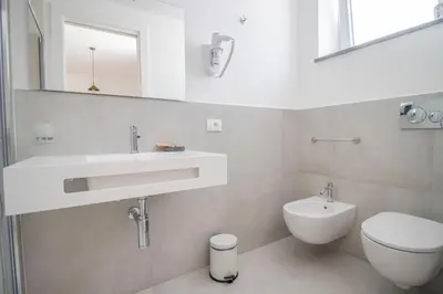 a white bathroom with a sink and a toilet at Hotel Arte Mare in San Vito lo Capo
