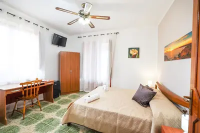 a bedroom with a bed and a desk and a ceiling fan at B&B Giardino dei Cedri in Trabia